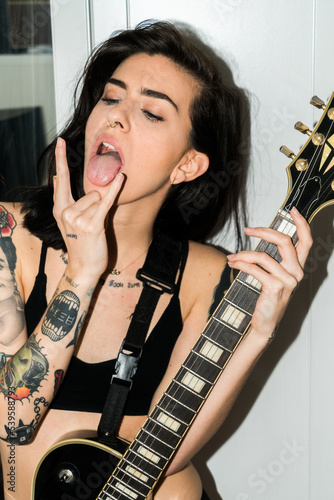 Fotografie Young woman with an edgy look holding a black guitar