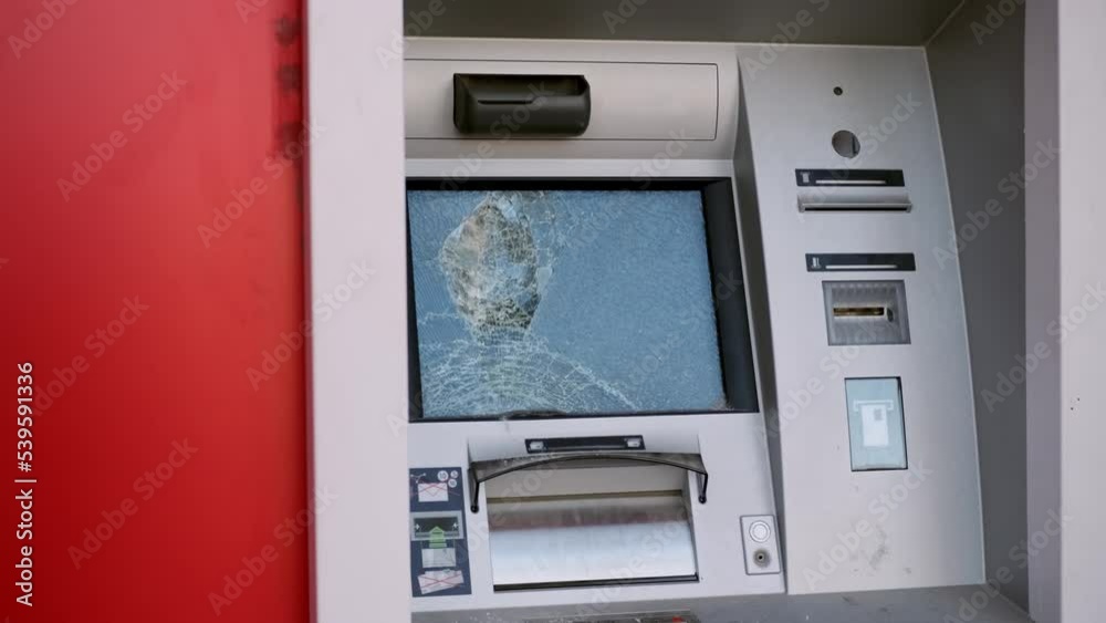 Broken glass of red bank ATM on street. touchscreen of banking machine for issuing and receiving cash is vandalized as result of riots in streets. concept of not receiving money or credit, disregard. Broken glass of red bank ATM on street. touchscreen of banking machine for issuing and receiving cash is vandalized as result of riots in streets. concept of not receiving money or credit, disregard.
