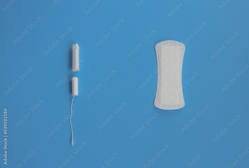 On a blue background lies a sanitary pad and a tampon. Women Health. Soft focus On a blue background lies a sanitary pad and a tampon. Women Health. Soft focus