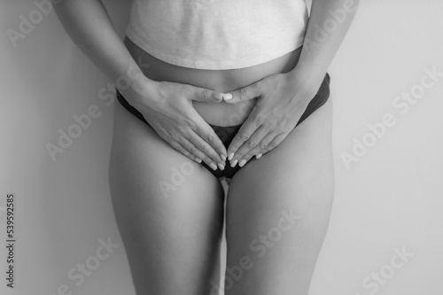 The girl holds her stomach with her hands. Diseases of the genitourinary system. Women Health. Black and white. Soft focus