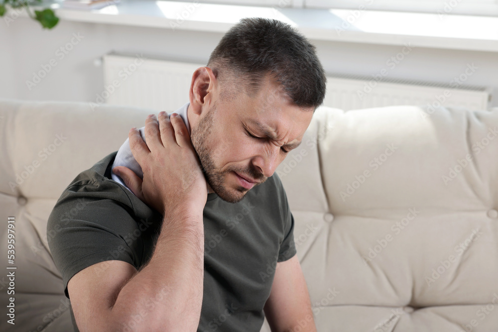 Man using heating pad on sofa at home Man using heating pad on sofa at home
