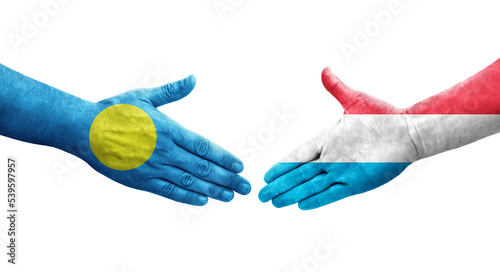 Handshake between Luxembourg and Palau flags painted on hands, isolated transparent image.