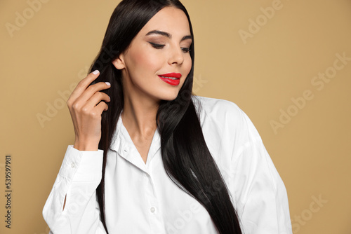 Portrait of young woman wearing beautiful red lipstick on beige background