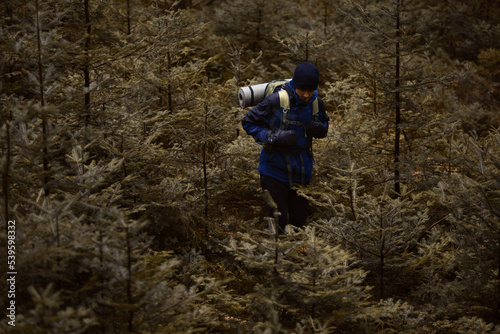 A caucasian male hiker with a backpack hiking in a pine forest.
