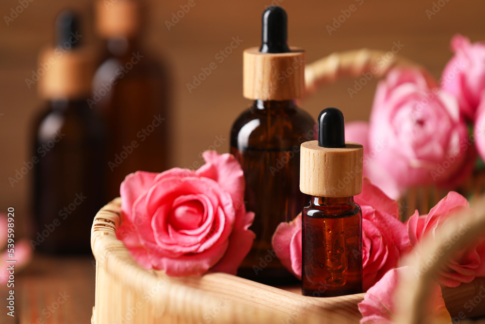 Tray with bottles of essential rose oil and flowers on table, closeup Tray with bottles of essential rose oil and flowers on table, closeup
