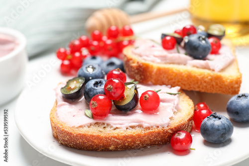 Tasty sandwiches with cream cheese, berries and honey, closeup