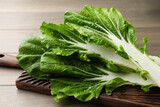 Leaves of fresh green pak choy cabbage with water drops on wooden table, closeup