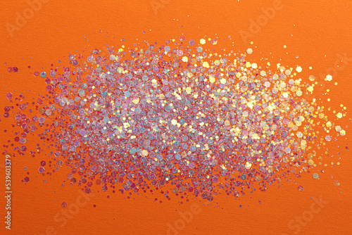 Shiny bright lilac glitter on orange background  flat lay