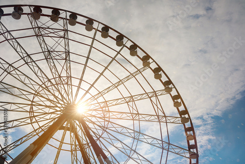 Beautiful large Ferris wheel against blue cloudy sky on sunny day  low angle view