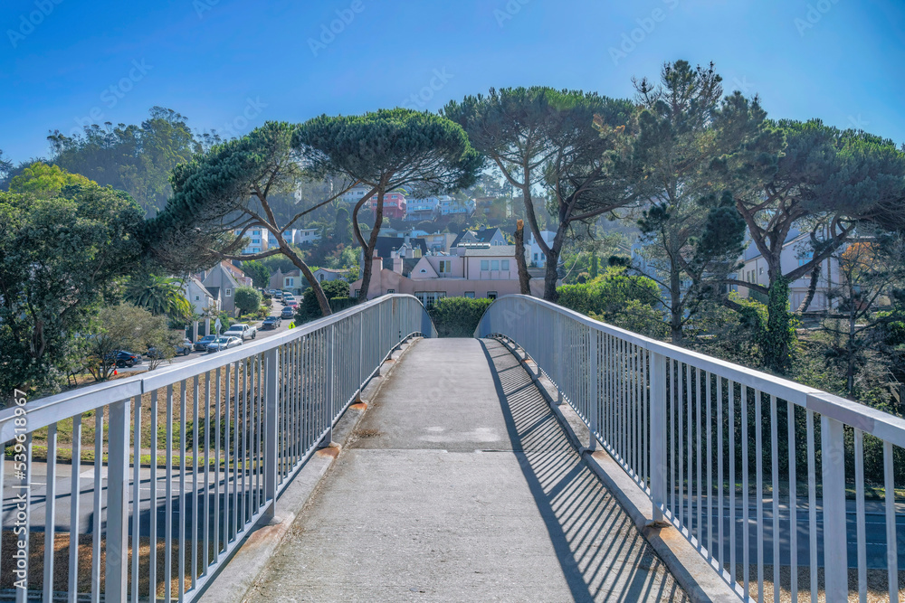 Narrow paved walkway overlooking houses and blue sky on a sunny day