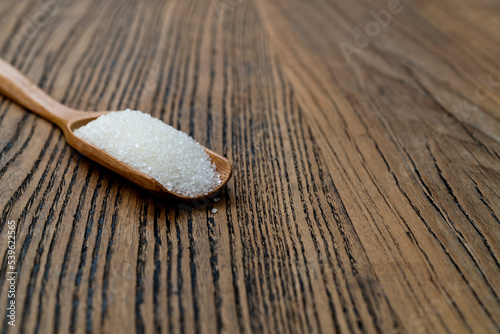 Wooden scoop with sugar crystals on the table