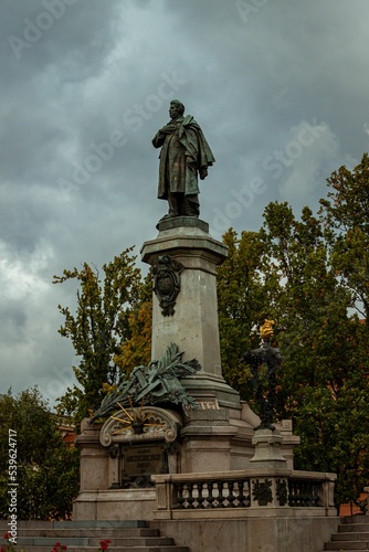 Vertical shot of Monument of Adam Mickiewicz against gray clouds photo