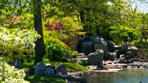 Green park with small waterfalls and rocky river on a sunny day