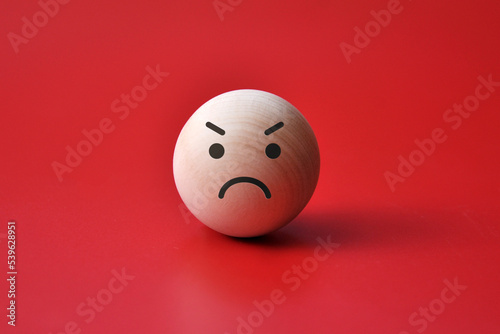 A wooden ball with an angry face. Symbol of anger