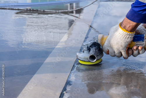 Worker in gloves with a small angle grinder is griding concrete road surface for more smooth and clean photo