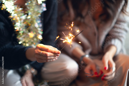 Sparklers in the hands of girls for Christmas or New Year. Front view.