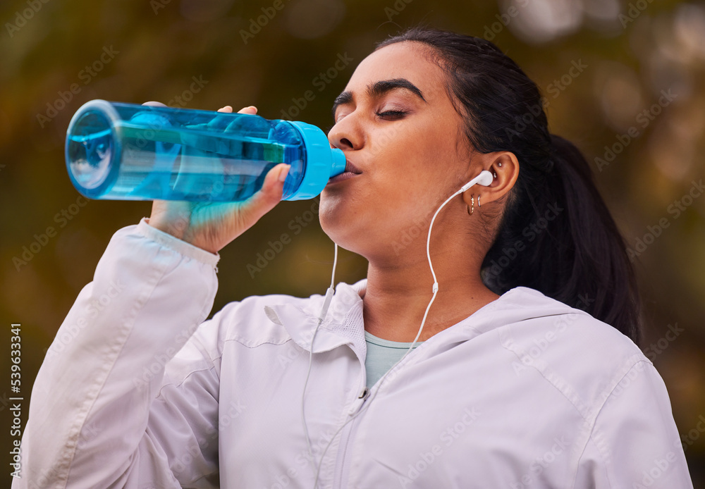 Fitness, runner and woman with bottle drinking water while running in forest for exercise, cardio workout or sports. Marathon training, thirsty or young girl with liquid hydration for wellness health Fitness, runner and woman with bottle drinking water while running in forest for exercise, cardio workout or sports. Marathon training, thirsty or young girl with liquid hydration for wellness health