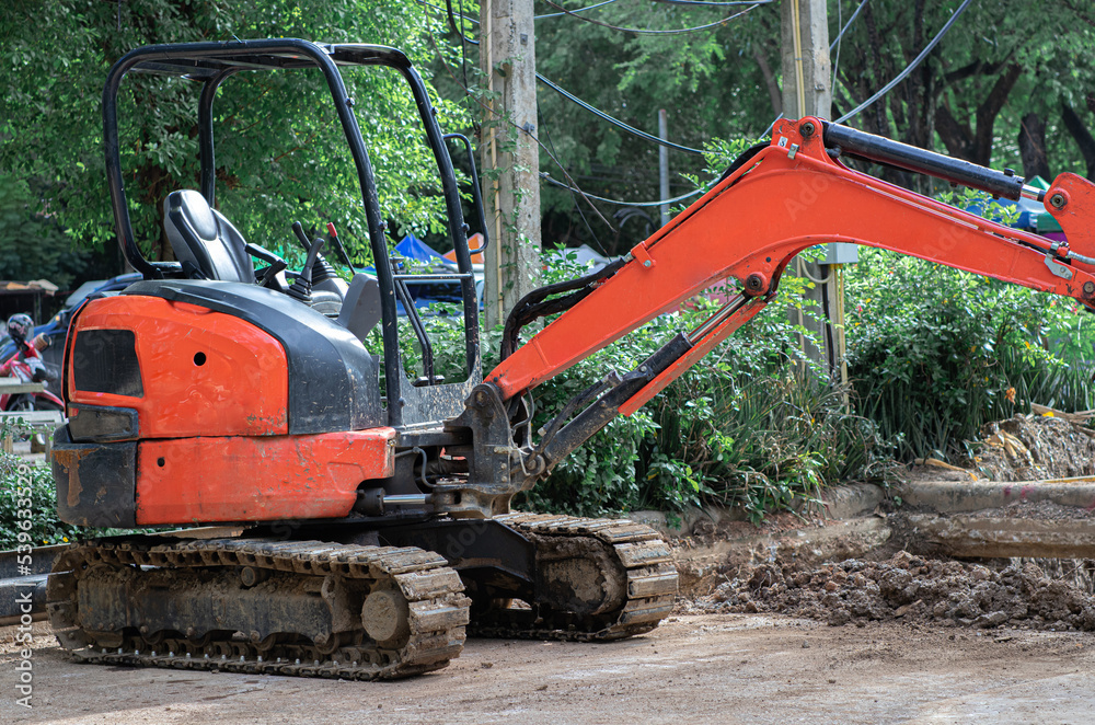 The orange mini Backhoe or Crawler excavator (Tracked excavator) is parked at the construction site The orange mini Backhoe or Crawler excavator (Tracked excavator) is parked at the construction site