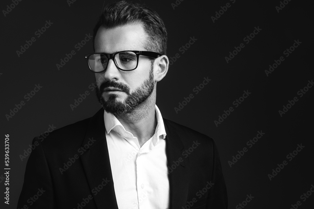 Closeup portrait of handsome confident stylish hipster lambersexual model. Sexy modern man dressed in elegant black suit. Fashion male posing in studio on dark background. In spectacles Closeup portrait of handsome confident stylish hipster lambersexual model. Sexy modern man dressed in elegant black suit. Fashion male posing in studio on dark background. In spectacles