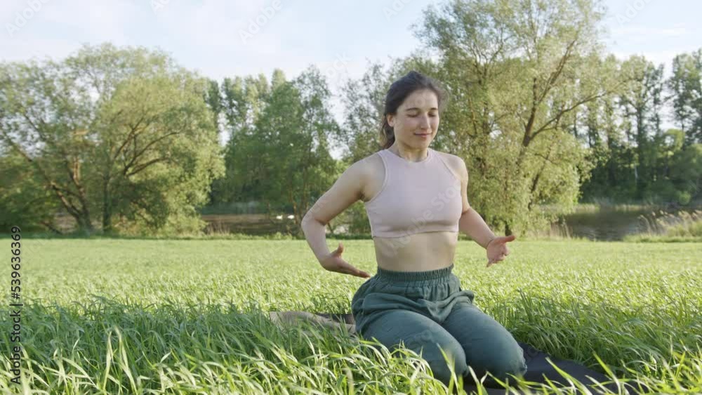 Determined woman does yoga breathing practice on green field Determined woman does yoga breathing practice on green field