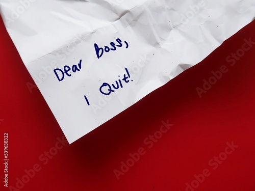On red background, crumpled paper with handwritten text DEAR BOSS I QUIT, concept of employee decides to leave work, quitting full time job after pandemic in the great resignation phenomenon