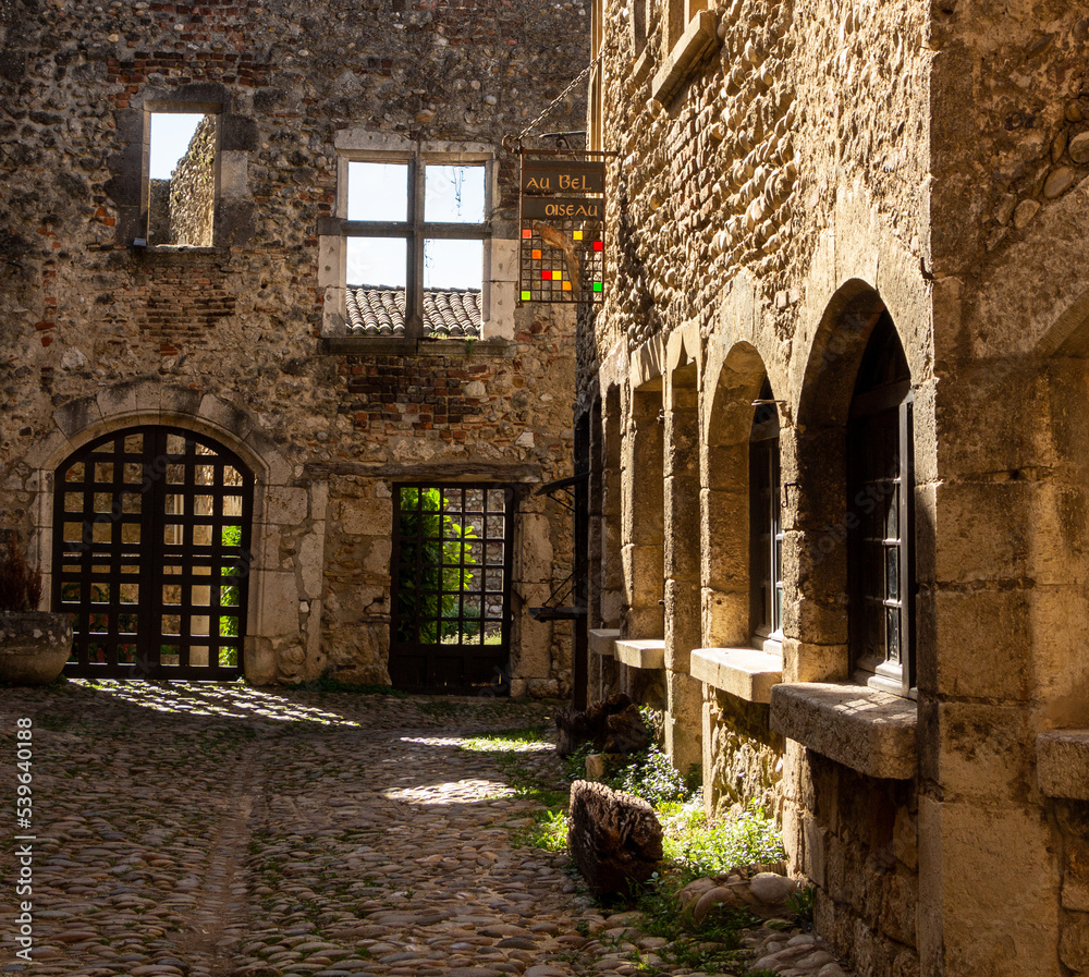 Old medieval street with stone houses, between light and shadow, in the famous village Pérouges, Ain.