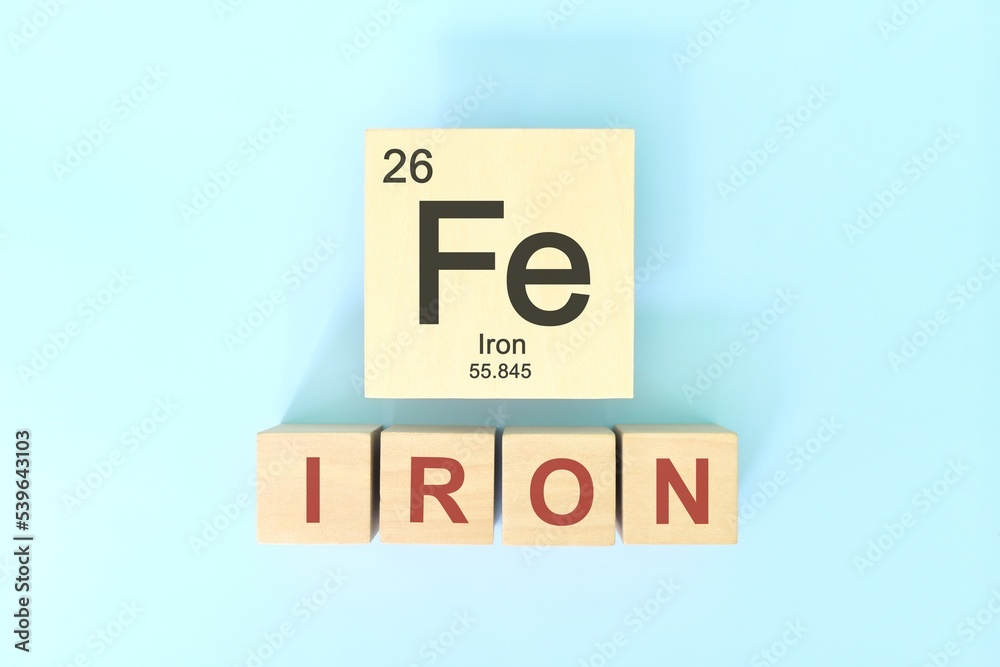 Iron chemical element symbol with atomic mass and atomic number in wooden blocks flat lay composition. Chemistry and Science concept.