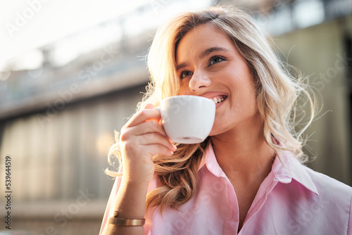 Closeup portrait of a blonde woman drinking coffee, street coffee shop