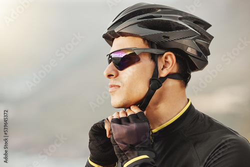 Fototapeta Naklejka Na Ścianę i Meble -  Cycling, helmet and sunglasses with a sports man being safe while outdoor for a ride on a cloudy day. Safety, cycle and fitness with a male athlete outside to exercise or workout for cardio health