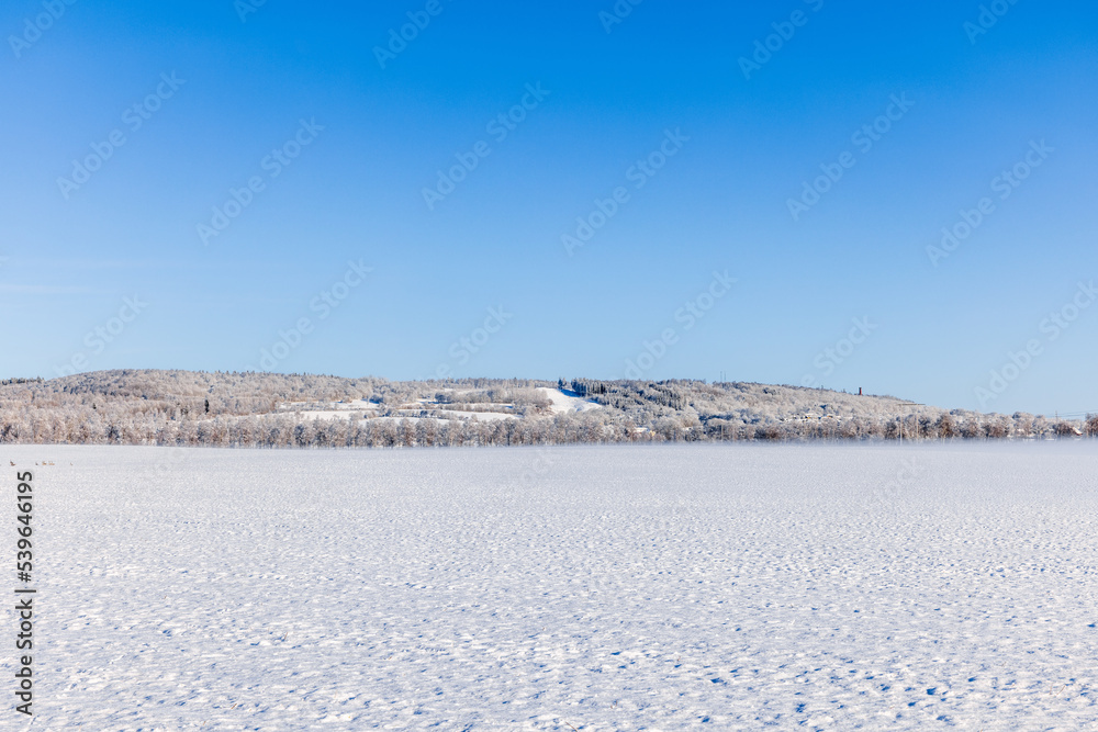 Snowy fields with a hill on a sunny winter day