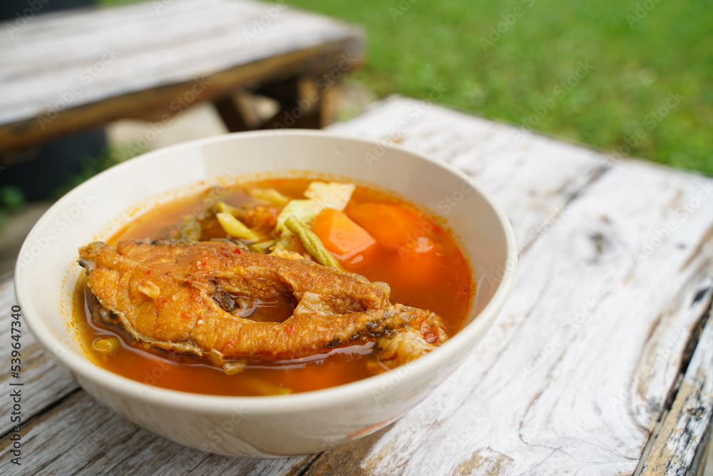 Tamarind curry with fried fish and vegetables on wooden floor - Thai style  That is delicious and has been very popular.