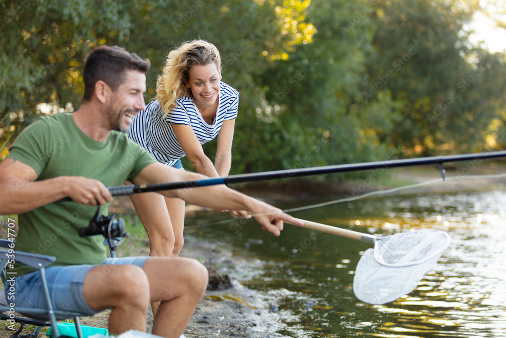 couple fishing at the river with fishing rod and net couple fishing at the river with fishing rod and net