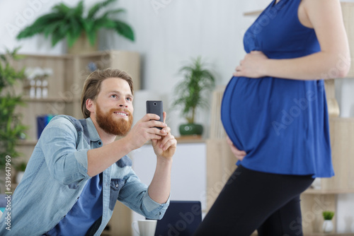 man takes a photo of pregnant woman