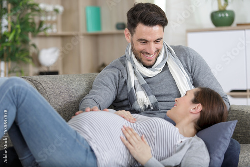pregnant woman and handsome man lying on sofa