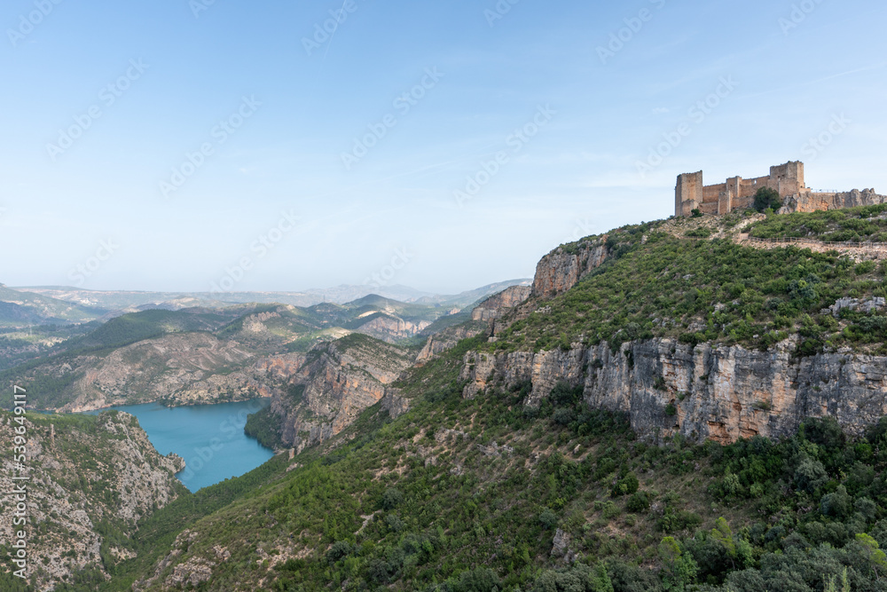 Beautiful landscape photo of mountains and trees where you can see the Chirel castle and the Cortes del Pallas reservoir, Valencian community, Spain