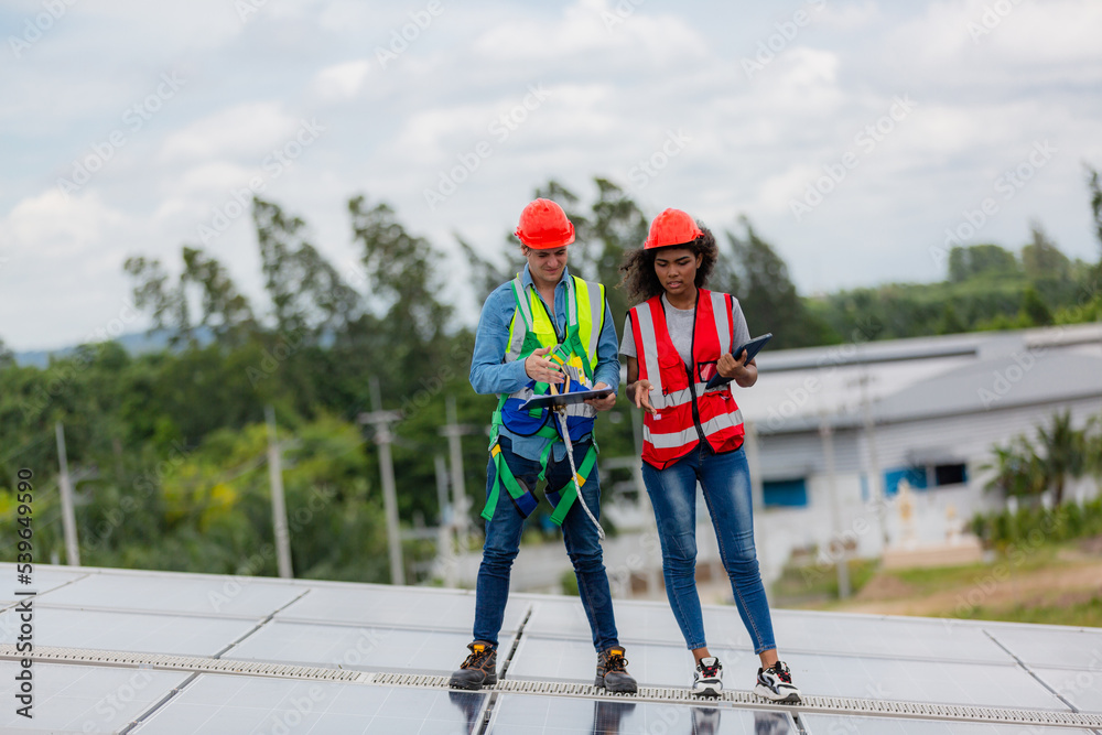 technician engineer working on checking maintenance service with solar batteries near solar panels at sunny day in solar power plant station on rooftop, electricity energy of photovoltaic industrial