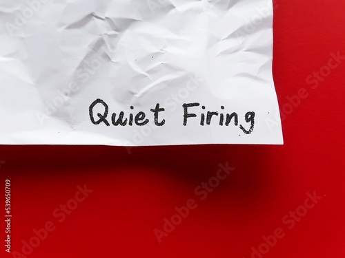 Crumpled paper on copy space red background with handwriting Quiet Firing - refers to employers who treat workers badly to the point they will quit, instead of firing them