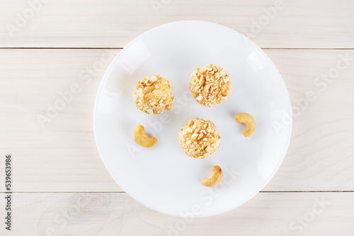 Traditional brazilian brigadeiro sweets with cashew nuts on a wooden table. Top view, flat lay.
