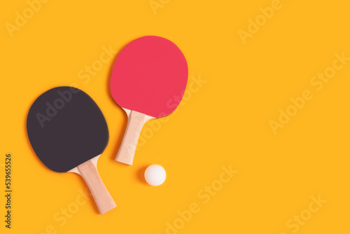 Tennis rackets and white ball on a yellow background. Ping pong concept with copy space. photo