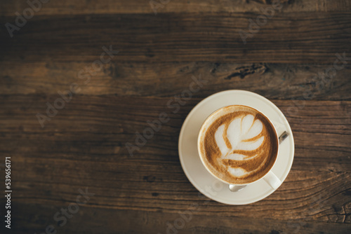 White cup with fresh cappuccino on wooden background