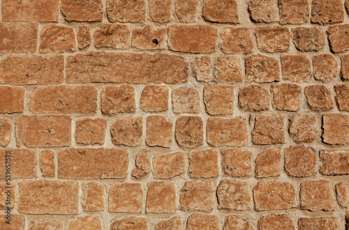 Front view of stone wall background. The stones are light orange in colour.