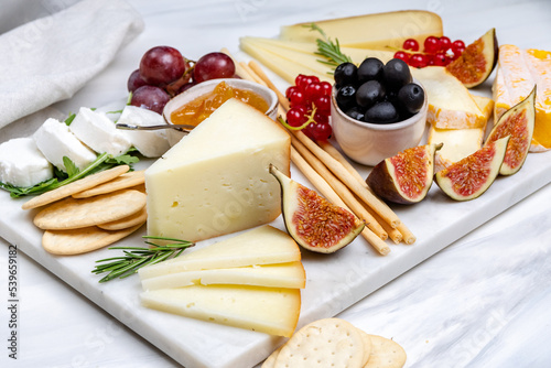 French Cheese platter with camembert, brie, Gorgonzola, parmesan, honey, figs and herbs. White background. Top view.