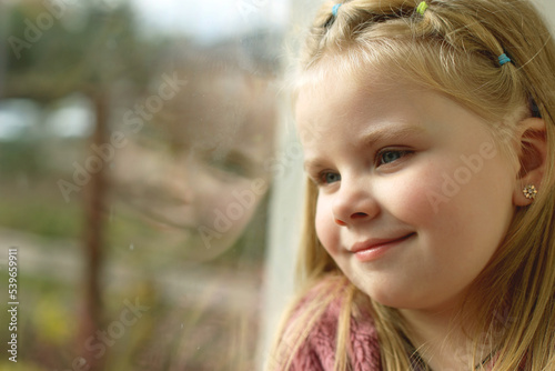 A small child near the window at home. The child is safe  sunlight on the face