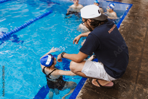 Obraz na plátně Latin swimming man trainer with chronometer talking some advices to teenagers sw