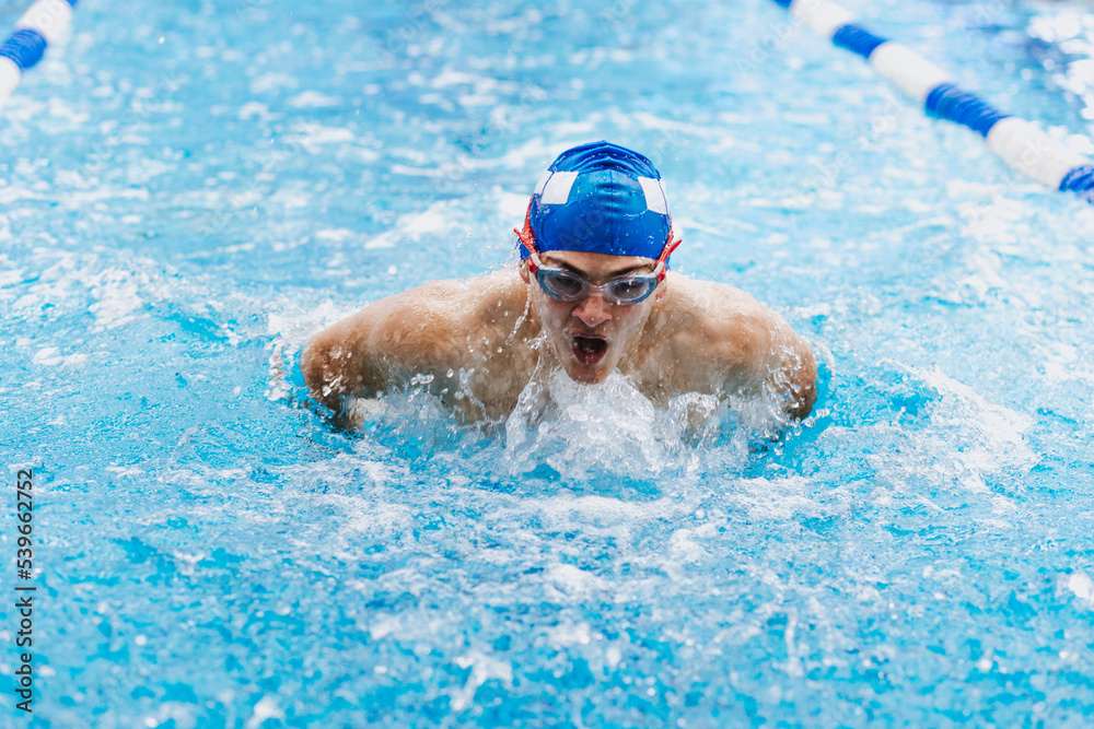 hispanic young man swimmer athlete wearing cap and goggles in a swimming training at the Pool in Mexico Latin America	