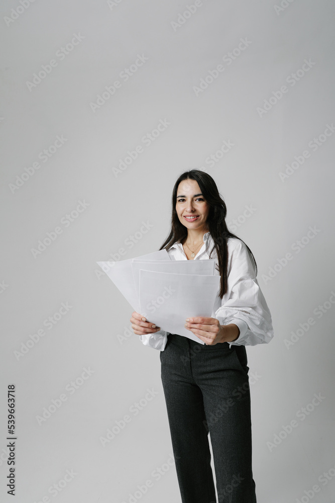 Vertical portrait of woman, mentor coach stays over white wall holds papers. Vertical portrait of woman, mentor coach stays over white wall holds papers.