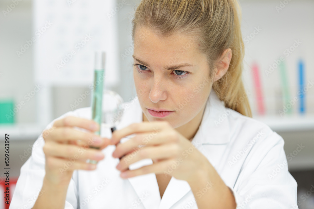 woman scientist adding liquid to test tube with pipette woman scientist adding liquid to test tube with pipette
