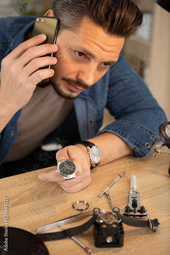 a man on the phone is repairing a watch