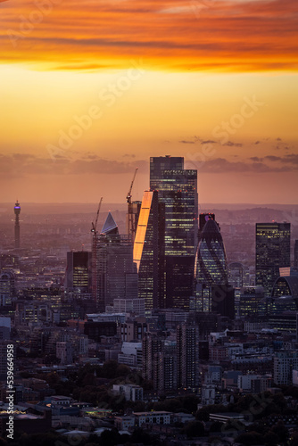 The modern office skyscrapers at the City of London, England, during a golden sunset with reflections in the glass facades