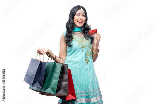 Indian woman carrying shopping bags while holding credit card